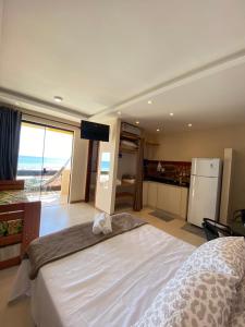 a bedroom with a large white bed and a television at Varandas ao mar loft 302 Praia Grande in Arraial do Cabo