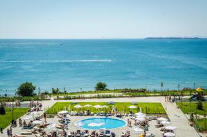 a group of people standing around a swimming pool next to the ocean at Premier Fort Sands Resort - Full Board in Sunny Beach