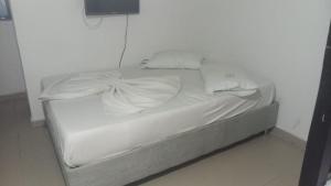 an unmade bed with white sheets on it in a room at HOTEL VISTA AL MAR habitacion para 2 personas in Rodadero