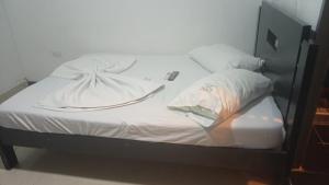 a bed with white sheets and pillows on it at HOTEL VISTA AL MAR habitacion para 2 personas in Rodadero