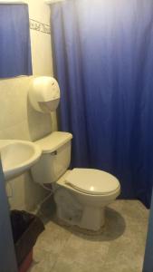 a bathroom with a white toilet and a blue shower curtain at HOTEL VISTA AL MAR habitacion para 2 personas in Rodadero