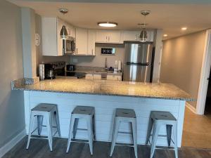 a kitchen with a counter with four stools at it at Large Myrtle Beach Condo, Fully Renovated in Myrtle Beach