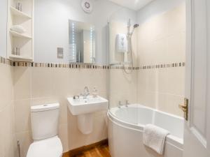 a bathroom with a toilet and a sink and a bath tub at Hardys Cottage in Overstrand
