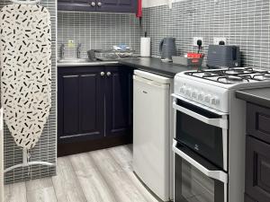 a kitchen with black cabinets and a white stove at Dairy Cottage - 28344 in Staintondale