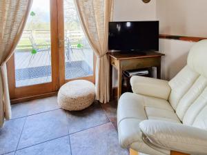 een woonkamer met een bank en een televisie bij Y Dderwen At Brynglas Farm in Llanfair Caereinion