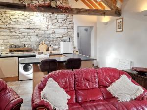 a living room with a red couch and a kitchen at Y Dderwen At Brynglas Farm in Llanfair Caereinion
