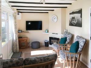 a living room with a couch and chairs and a tv at Bullrushes in Horning