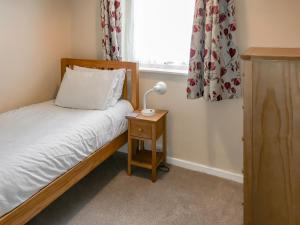 a bedroom with a bed and a lamp on a night stand at Bullrushes in Horning