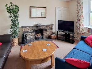 a living room with a table and a fireplace at Lilac Cottage in Hawes