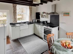 a kitchen with white cabinets and a bowl of fruit on a table at Lilac Cottage in Hawes