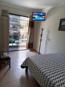 1 dormitorio con 1 cama y TV en la pared en Departamentos San Luis, en Tarija