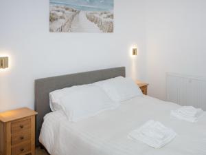 a bedroom with a white bed and a painting on the wall at Criffel Cottage in Ruthwell