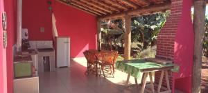 a kitchen with a table and chairs on a red wall at Pousadinha RoSi. in Santa Bárbara do Rio Pardo