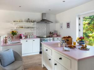 a kitchen with white cabinets and a pink counter top at The Mallard-uk46920 in Newby Bridge