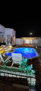 ein großer blauer Pool mit Stühlen in einem Garten in der Nacht in der Unterkunft منتجع سمايل القريات in Qurayyat