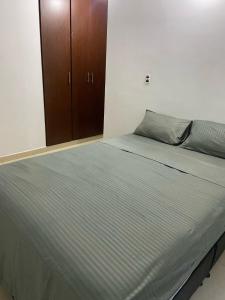 a large bed in a bedroom with a wooden cabinet at Habitación en Apartamento amplio cómodo y equipado in Cúcuta