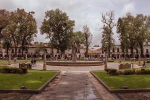 a courtyard of a building with trees and a fountain at Mansion de los Sueños in Pátzcuaro