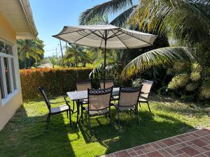 una mesa y sillas con una sombrilla en la hierba en Little paradise en Tela