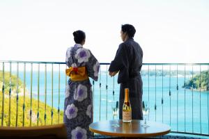 Dos mujeres de pie en un balcón con vistas al agua en Sunperla Shima en Shima
