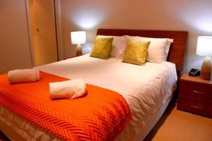 a bedroom with a large bed with an orange blanket at Loka Santi 10 - Beachfront unit in Agnes Water