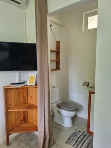 a bathroom with a toilet and a tv on a cabinet at Pension ANAPA LODGE - MOOREA in Vaianae