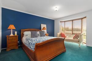 a bedroom with a bed and a blue wall at Killarney Coastal Cottage in Rye