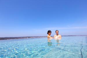 two women standing in the water on the beach at Ooedo Onsen Monogatari Premium Yamashitaya in Kaga