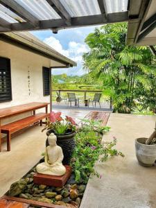 una statua di Buddha seduta su un patio con piante di Art & Soul Villa a Pacific Harbour