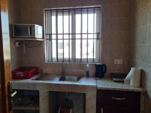 una pequeña cocina con fregadero y ventana en Cozy Escape in Accra by Manna Hospital, en Accra