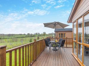 a wooden deck with a table and an umbrella at Winnal View - Uk46891 in Kinlet