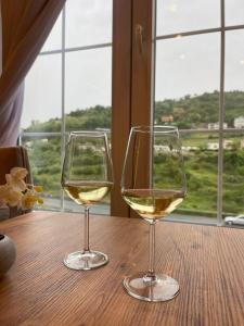 due bicchieri di vino bianco seduti su un tavolo di legno di Reign Hotel a Vorë