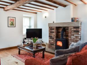 a living room with a fireplace and a couch at Summerville Cottage in Kirkby Stephen