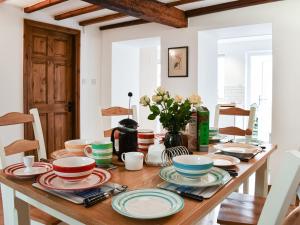 a wooden table with plates and bowls on it at Summerville Cottage in Kirkby Stephen