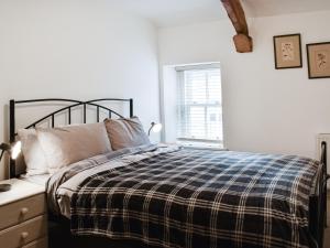 a bedroom with a bed with a plaid blanket and a window at Summerville Cottage in Kirkby Stephen