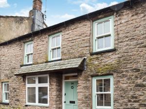 an old brick house with a green door and windows at Summerville Cottage in Kirkby Stephen