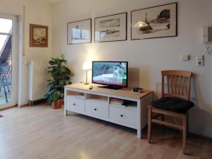 un salon avec une télévision et une chaise dans l'établissement Haus Tante Clara Skipperkoje, Whg 20, Kukshörner Weg 8b, à Dangast