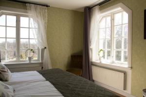 a bedroom with a bed and two windows at Baldersnäs Herrgård in Dals Långed