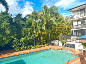 a swimming pool in front of a house with palm trees at Seaside Oasis 2Beds Apt with Free Parking in Gold Coast