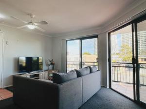 a living room with a couch and a television at Seaside Oasis 2Beds Apt with Free Parking in Gold Coast