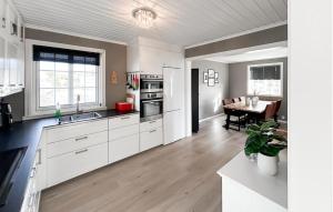 una cucina con armadi bianchi e un tavolo di Gorgeous Home In Lindesnes With Kitchen a Spangereid