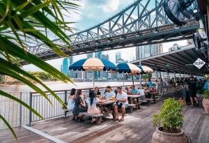 a group of people sitting at tables under a bridge at Balmoral Apartment - Airy & Light-filled City Edge Comfort Stay in Brisbane