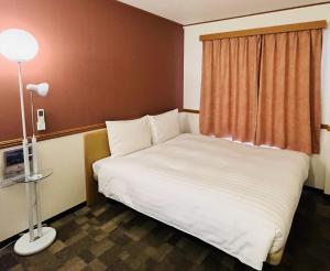 una camera con un letto bianco e una finestra di Toyoko Inn Ueda Ekimae a Ueda