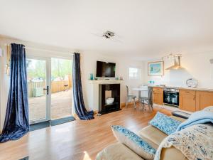 a living room with a couch and a table and a kitchen at River Cabin in Little Baddow