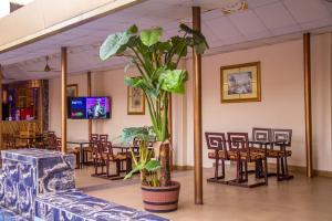 a room with tables and chairs and a plant at Francinesplace Hotel in Uyo