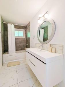 a white bathroom with a sink and a mirror at The Lilac Bungalow in Kingston