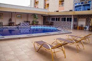 a swimming pool with two chairs and a swimming pool at Francinesplace Hotel in Uyo