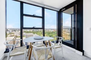 a dining room with a table and chairs and large windows at City Bloom - A Cosy Haven in Melbourne's Epicentre in Melbourne