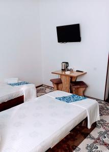Cette chambre comprend 2 lits et une table avec une télévision. dans l'établissement Gavhar House, à Khiva