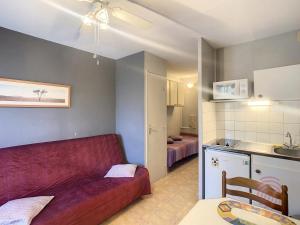 ein Wohnzimmer mit einem roten Sofa und einer Küche in der Unterkunft Studio Charmant à Lamalou-les-Bains, Balcon, Wifi, Proche Thermes et Nature - FR-1-451-208 in Lamalou-les-Bains