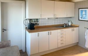 a kitchen with white cabinets and a sink at Nice Home In Smøla With House Sea View in Smøla